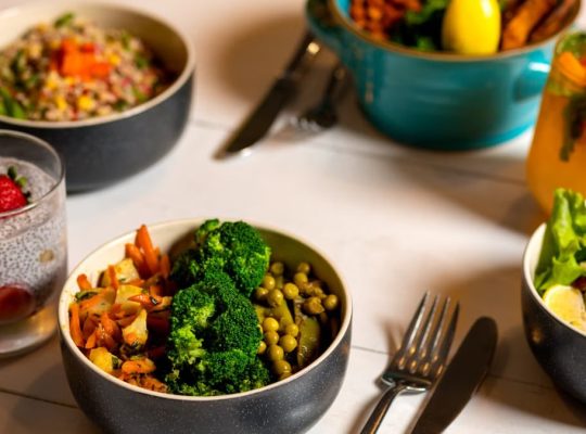 Delicious colorful bowls of salad and fresh beverages on a white table, perfect for healthy dining.