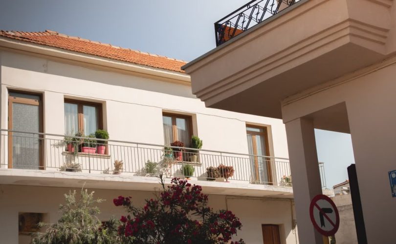 Traditional Greek house facade with potted plants and balcony details.